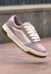Roosa sametist sneakers, millel on valged aktsendid, paksed paelad, pehme kaelus ja tekstureeritud kummitald. Mudeli logo on puhvis keeles.