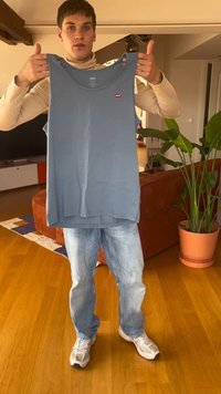 Ανοιχτό μπλε αμάνικο μπλουζάκι με στρογγυλή λαιμόκοψη, φτιαγμένο από μαλακό ύφασμα, με μικρό κόκκινο λογότυπο Levi's μπροστά, κρατημένο από ένα άτομο.