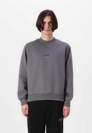 Gray sweatshirt with ribbed crew neck and cuffs. Features black "ESS.WRD." text on chest. Paired with black pants for a complete outfit.