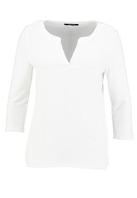 Camicia bianca a maniche lunghe realizzata in tessuto morbido. Presenta un scollatura a V e un taglio dritto. Progettata senza motivi o decorazioni.