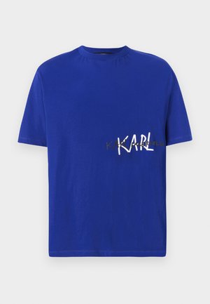 Mėlynas medvilninis marškinėliai su apvalia iškirpte. Yra balta užrašas "KARL" ir papildomas auksinis tekstas, trumpomis rankovėmis ir įprasto kirpimo.