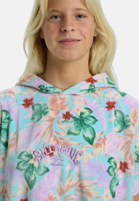 Sudadera con capucha en una suave tela texturizada con un patrón floral en tonos pastel, hojas verdes y flores rojas; logo bordado en púrpura.