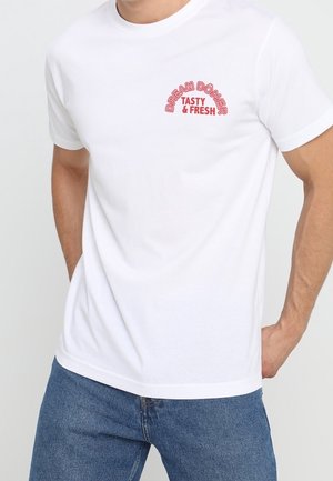 White cotton t-shirt featuring red text "DREAM DÖNER" and "TASTY & FRESH" in a semi-circle design above the left chest area.