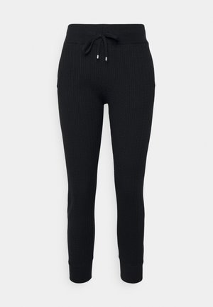 Pantalon de jogging noir en tricot avec ceinture côtelée, poignets aux chevilles et fermeture à cordon, présenté sur un fond neutre.