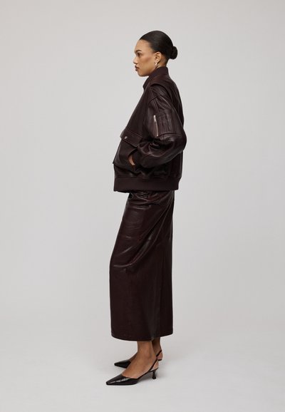 Bruine leren bomberjack, bijpassende bruine leren rok, elegante zwarte kitten heels. Textuur materiaal, gestructureerd ontwerp, minimalistische stijl.