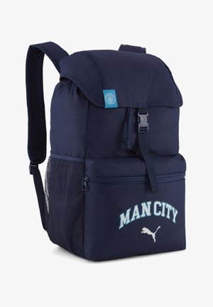 Marineblå rygsæk med klap og spænde, netlomme på siden, forreste lynlåslomme, "MAN CITY" tekst og Puma-logo på den forreste lomme.