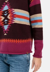 Mehrfarbiger Strickpullover mit einem geometrischen Muster in Burgunderrot, Pink, Orange, Blau und Creme sowie gerippten Bündchen und Saum.