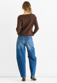 Ruskea ribbed neulepusero, siniset leveälahkeiset farkut, vyötäröltä istuvat, hieman lyhennetyt ja siisti viimeistely.