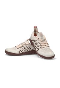 Un par de zapatillas de punto de color beige claro con suelas marrones y cordones rosados, una zapatilla descansando de lado.