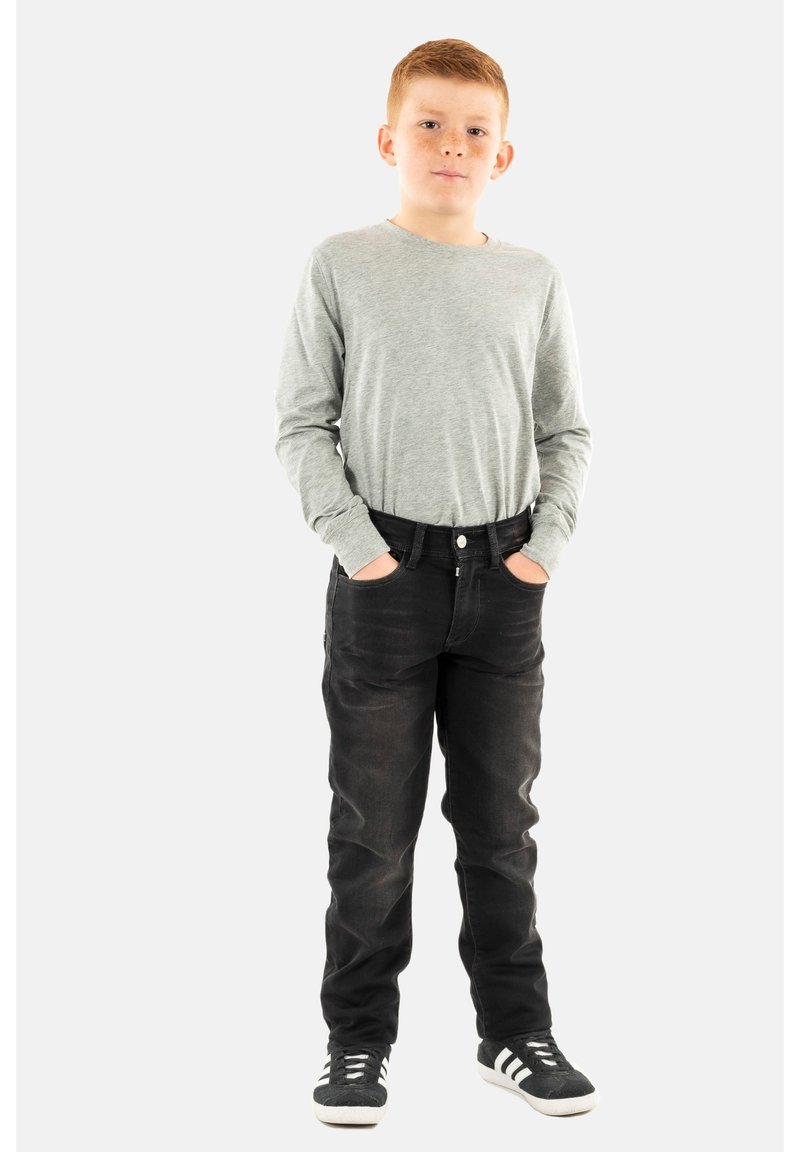 Camisa de manga larga gris combinada con jeans de mezclilla negros. Los jeans tienen un corte clásico y una sutil textura desteñida, complementados por zapatillas negras.