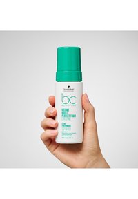 Bouteille cylindrique en mousse blanche avec un capuchon turquoise, étiquetée "Volume Boost Perfect Foam". Contient 150 ml de produit coiffant pour cheveux fins.