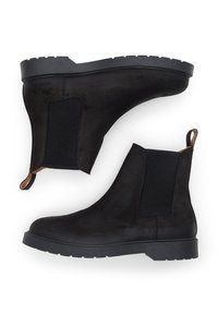 Černé semišové Chelsea boty s elastickými bočními panely, kontrastními hnědými akcenty a texturovanou gumovou podrážkou. Zakulacená špička a poutko pro snadné obutí.