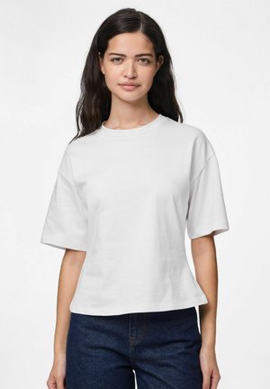 Weißes Baumwoll-T-Shirt mit kurzen, weiten Ärmeln, Rundhalsausschnitt und lockerer Passform, kombiniert mit dunkelblauen Jeans.