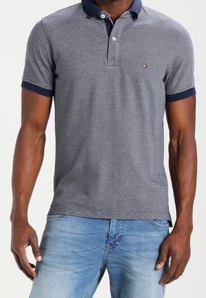 Navy- und grau strukturiertes Poloshirt mit kurzen Ärmeln, einem kontrastierenden Kragen, zwei Knöpfen und einem kleinen Logo auf der linken Brust.
