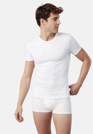 Camiseta blanca ajustada y bóxers blancos, hechos de una tela suave, con un cuello redondo clásico y mangas cortas.