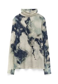 Langsleeve coltrui in lichtbeige met donkerblauwe abstracte patronen. De stof lijkt zacht met variërende texturen en een onregelmatige zoom.