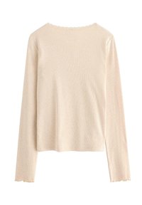 Beige ribbet langtærmet top med bølgede kanter ved halsudskæringen, manchetter og kant, vist fra bagpå på en hvid baggrund.