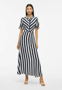 Randig skjortklänning i marinblått och vitt, med knappstängning fram, krage och korta ärmar. Golvlång med en avslappnad passform.