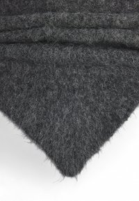 Mørkegrå uld tørklæde med en blød, tekstureret overflade og rå kanter, der har en trekantet form og lagdelte folder.