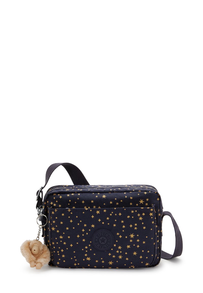 Bolsa de tela de color azul marino con un patrón de estrellas doradas, forma rectangular, cierre con cremallera y correa ajustable. Incluye un pequeño llavero de león de felpa.