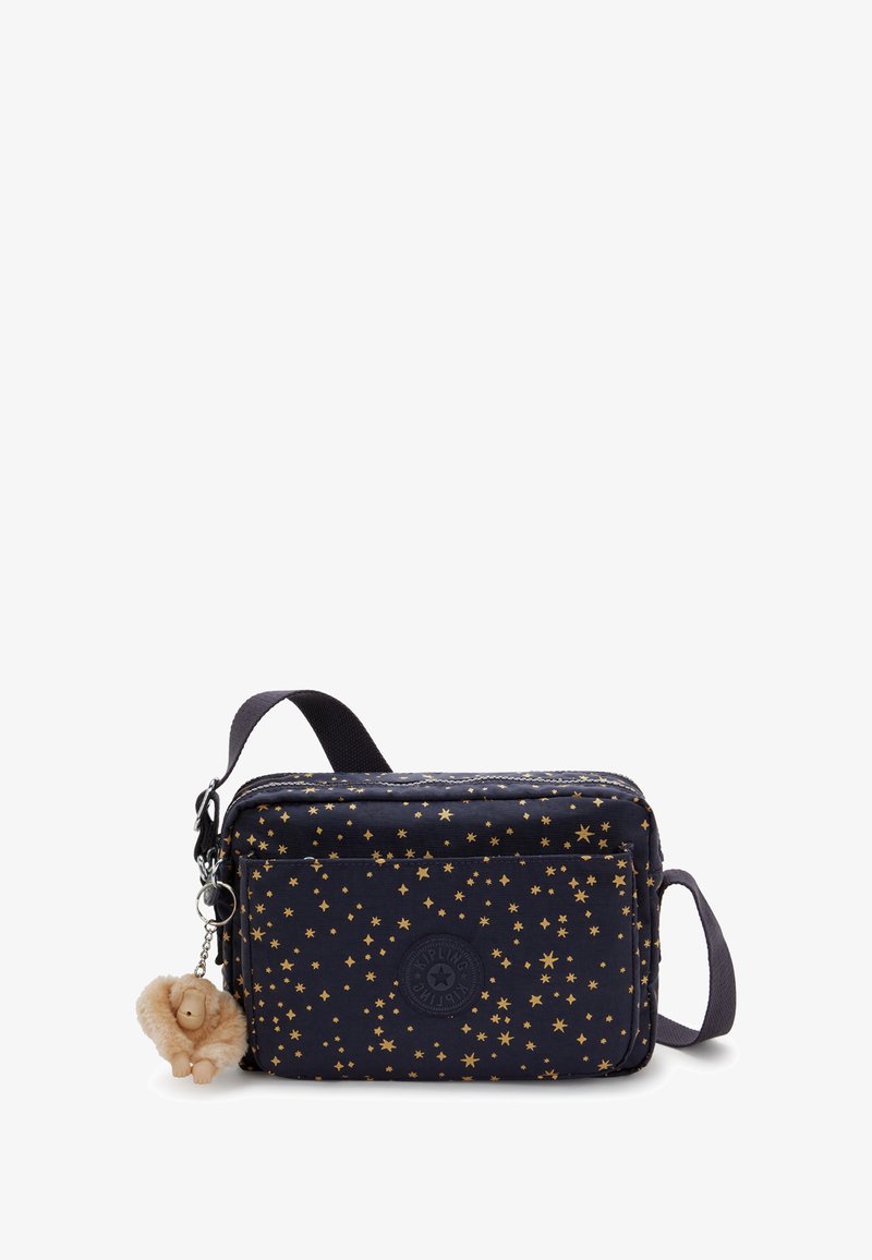 Marineblaues Stofftasche mit goldenem Sterne-Muster, rechteckiger Form, Reißverschluss und verstellbarem Tragegurt. Enthält ein kleines, plüschiges Löwen-Schlüsselanhänger-Detail.