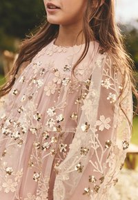 Heleroosa kleit lilleliste tikandite, kihilise tulliga ja metallsete helvestega. Omaduseks on ümargune kaelus ja peen tekstuur.