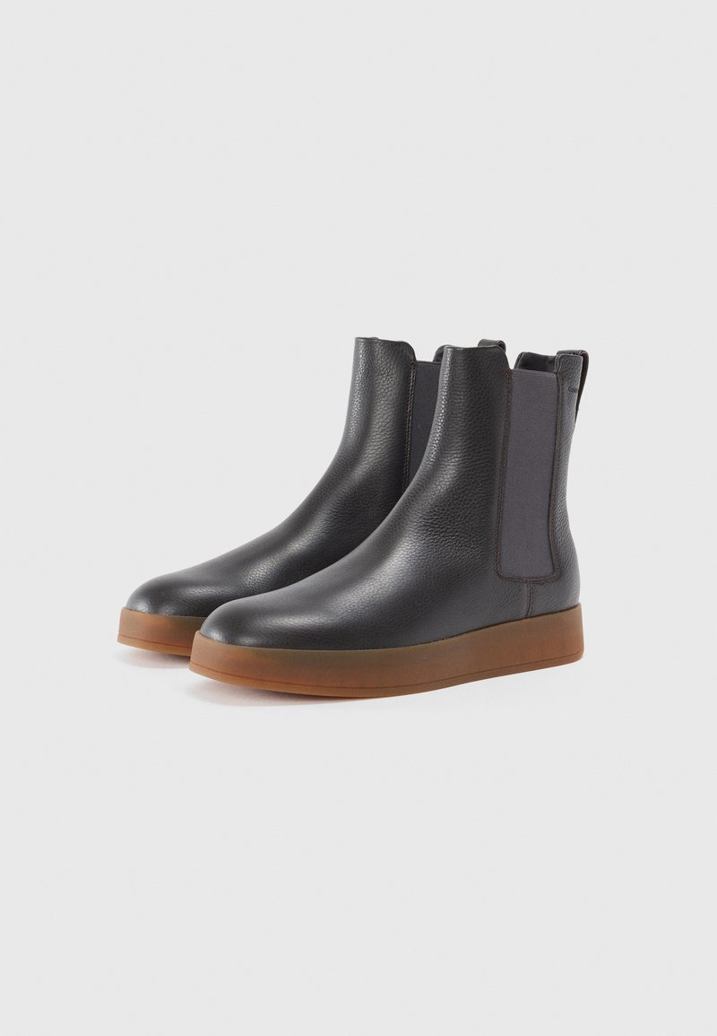 Schwarze Lederknöchelstiefel mit elastischen Seitenteilen, runder Zehenpartie und einer strukturierten Oberfläche. Sie verfügen über eine kontrastreiche gummierte Sohle in Beige.