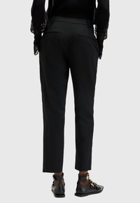 Svarta skräddarsydda byxor med slim fit, med bakfickor och en smidig struktur. Matchas med svarta skor med dekorativt guldfäste.