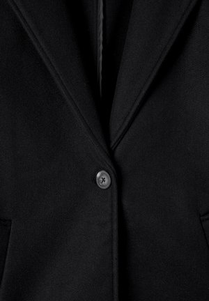 Blazer in lana nera con colletto a punta, chiusura a un bottone e due tasche anteriori. Tessuto liscio e dettagli di design minimalisti.