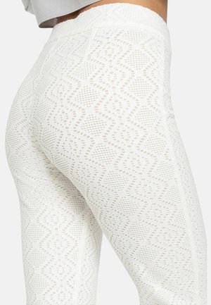Weiße Leggings mit einem strukturierten Strickmuster, das Diamantformen und Durchbrüche aufweist. Hoher Bund und figurschmeichelndes Design.
