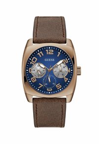 Reloj para hombre de Guess con caja en oro rosa, esfera azul marino, grandes números blancos, dos subesferas plateadas y correa de cuero marrón.