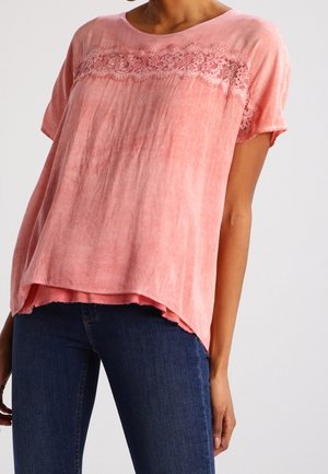 Vaaleanpunainen lyhythihainen paita, jossa on pitsiyksityiskohta kaula-aukossa. Rentoa mallia ja hieman pidempi takapääntie. Struktuuripintainen kangas.