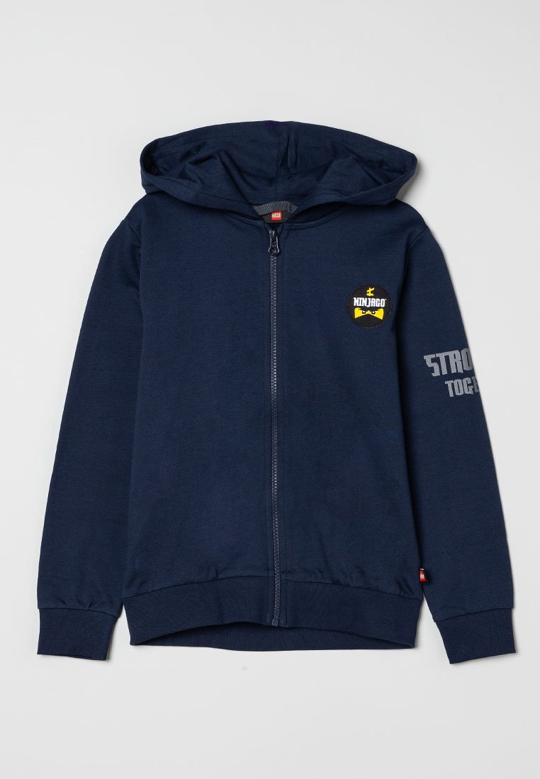 Marineblaue Zip-Hoodie mit Kapuze, "Ninjago"-Logo auf der Brust, und das Wort "STRONG" teilweise auf dem rechten Ärmel sichtbar.