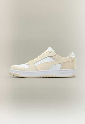 Basket basse beige et blanche Puma avec empiècements en daim, boîte d’orteils perforée, fermeture à lacets et semelle en caoutchouc griffée.