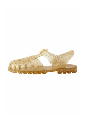 Sandal en gelée dorée transparente avec une sangle et une fermeture à boucle, présentant des découpes, une semelle texturée et une finition pailletée.