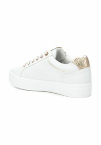 Zapatilla blanca con textura tejida en los laterales, detalles en dorado en el talón y los ojales, y una suela blanca redondeada.