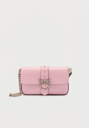 Sac bandoulière en cuir rose avec une sangle chaîne argentée, rabat avant et fermoir orné de deux oiseaux sur un anneau circulaire.