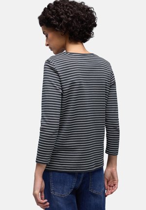 Mørkegrå langærmet skjorte med hvide horisontale striber, rund halsudskæring og en tætsiddende pasform, kombineret med blå jeans.