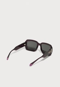 Purple plastic sunglasses with square lenses, dark grey lenses, and contrasting pink tips on the arms. Gold "Polaroid" branding on the side.