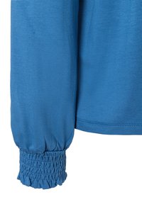 Blaues Langarmoberteil mit einer glatten Textur und gerafftem, elastischem Bündchen. Der Stoff erscheint leicht reflektierend und leicht.