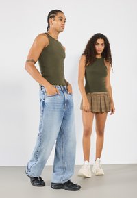 Zaļi riboti bezpiedurkņu topi, gaiši zili plaša kāju džinsi, dimantu miniskirts ar krokām un masīvas melnas un krēmkrāsas kedas.