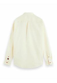 Langarmshirt in lichtgeel met een button-down kraag, rugplooi en manchetten met rode knoopaccenten. Soepele stoftextuur.