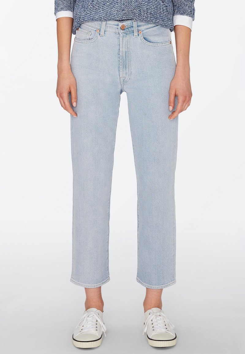 Světlomodré džíny s rovný střih, surovým lemem a designem s pěti kapsami, doplněné bílými teniskami s černými akcenty.