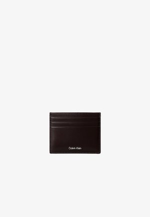Portacarte in pelle marrone scuro con sei fessure orizzontali per carte e logo "Calvin Klein" inciso in argento al centro in basso.