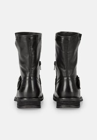 Stivali alla caviglia in pelle nera con una texture liscia, chiusure con cerniera sui lati e una suola leggermente robusta con tacco basso.