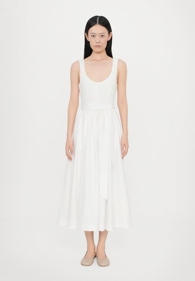 Robe midi blanche sans manches avec un décolleté en rond, un corsage ajusté et une jupe fluide. Présente une ceinture nouée à la taille et une texture de tissu lisse.