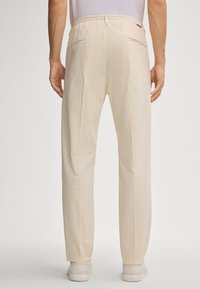 Beige, loszittende broek met een bijpassende elastische tailleband en twee achterzakken. Zachte textuur met een rechte pijp.