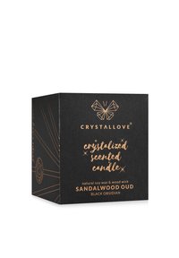 Emballage en boîte noire pour une bougie parfumée, mettant en avant une typographie en cuivre et des motifs géométriques. Les descriptions incluent "cire de soja naturelle" et "mèche en bois."