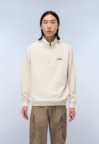 Cremefarbener Sweatshirt mit halbem Reißverschluss, Stehkragen, langen Ärmeln, gerippten Bündchen und kleinem Logo auf der Brust. Der Stoff wirkt weich.