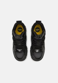 Sneaker alte nere con tomaia in pelle liscia, dettagli testurizzati, interno giallo e lacci neri. Presenta un logo prominente sulla linguetta.